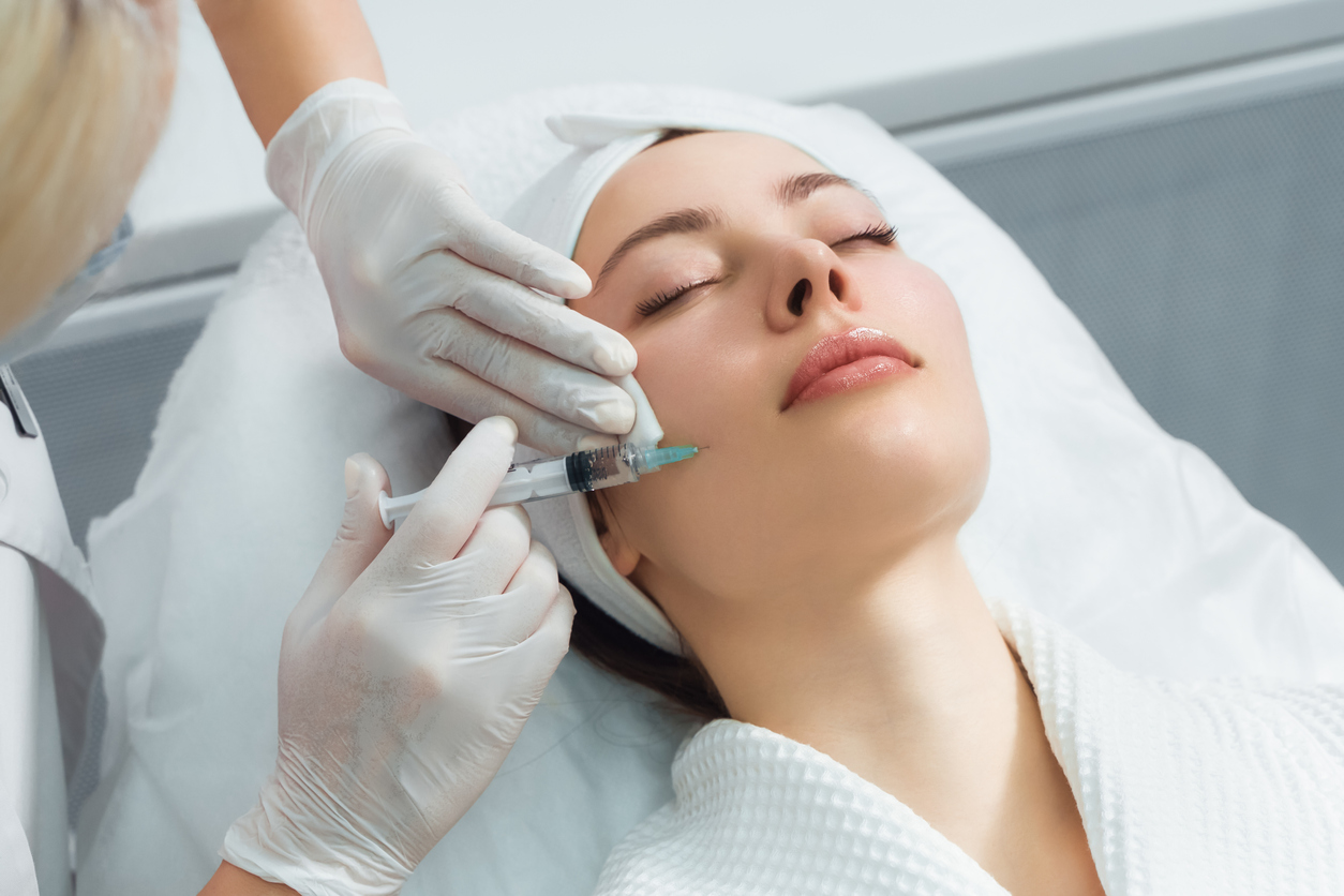 The doctor cosmetologist makes the rejuvenating facial injections procedure|Dr. Lanna holding dermal filler injection