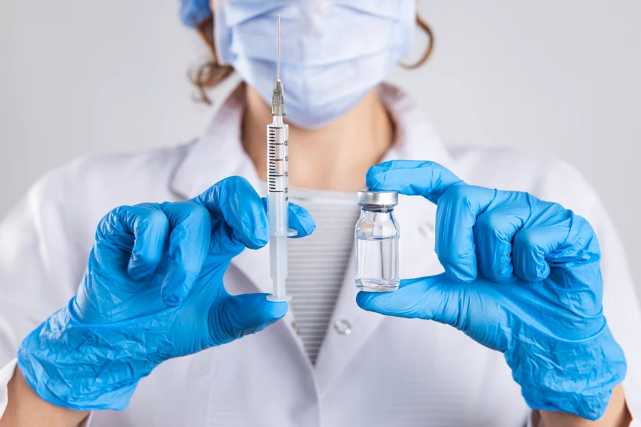 medical esthetician holding a syringe and a vial filled with dermal fillers